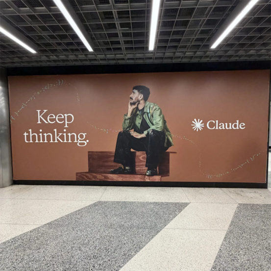 A billboard featuring a man sitting on steps, with urban scenery in the background.